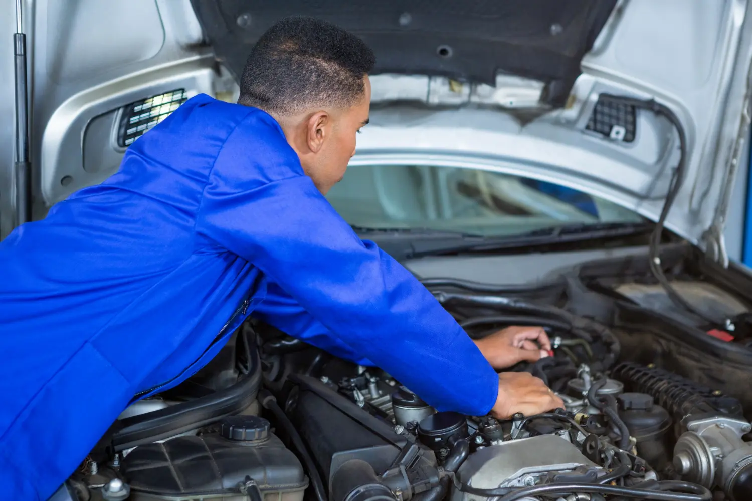 A mechanic working on an engine under an open bonnet
