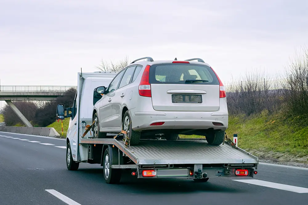 A flatbed recovery truck carrying a car on a UAE road